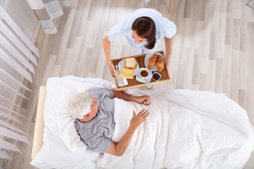 Elderly man being served breakfast in bed